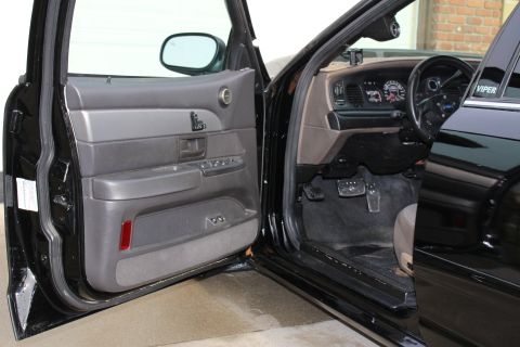 2003 Ford Crown Victoria - Photograph of a black sedan's open door showing the interior and dashboard, not a technical document.
