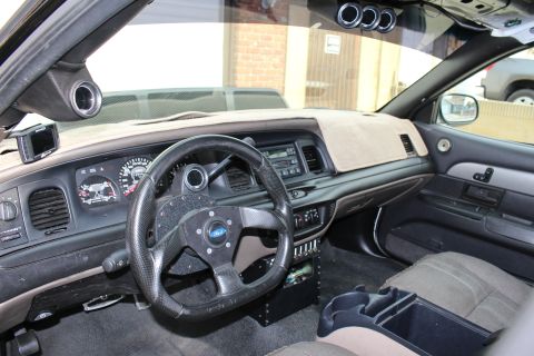2003 Ford Crown Victoria - Photograph of a modified sedan interior with dashboard and aftermarket steering wheel, not a technical document.