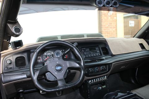 2003 Ford Crown Victoria - Photograph of a modified black sedan's dashboard and aftermarket steering wheel, not a technical document.