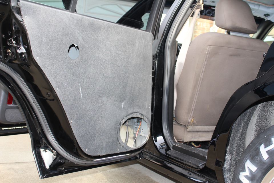 Open rear door with custom panel and rear seat of a black sedan