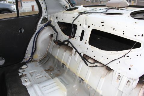 2003 Ford Crown Victoria - Photo of a stripped sedan interior showing the bare painted rear bulkhead, wiring, and floor.