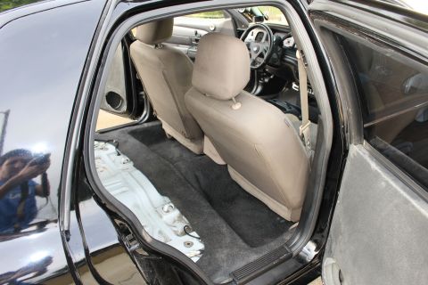 2003 Ford Crown Victoria - Photo of a black sedan interior with tan seats installed and the rear floor partly exposed.