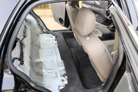 2003 Ford Crown Victoria - Photo of a black sedan's rear seat area with the floor pan exposed during restoration.