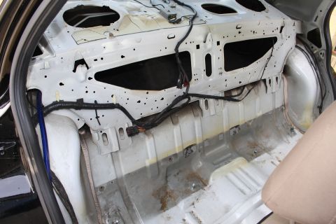2003 Ford Crown Victoria - Photo of a stripped sedan showing the bare rear bulkhead, wiring harness, and floor.