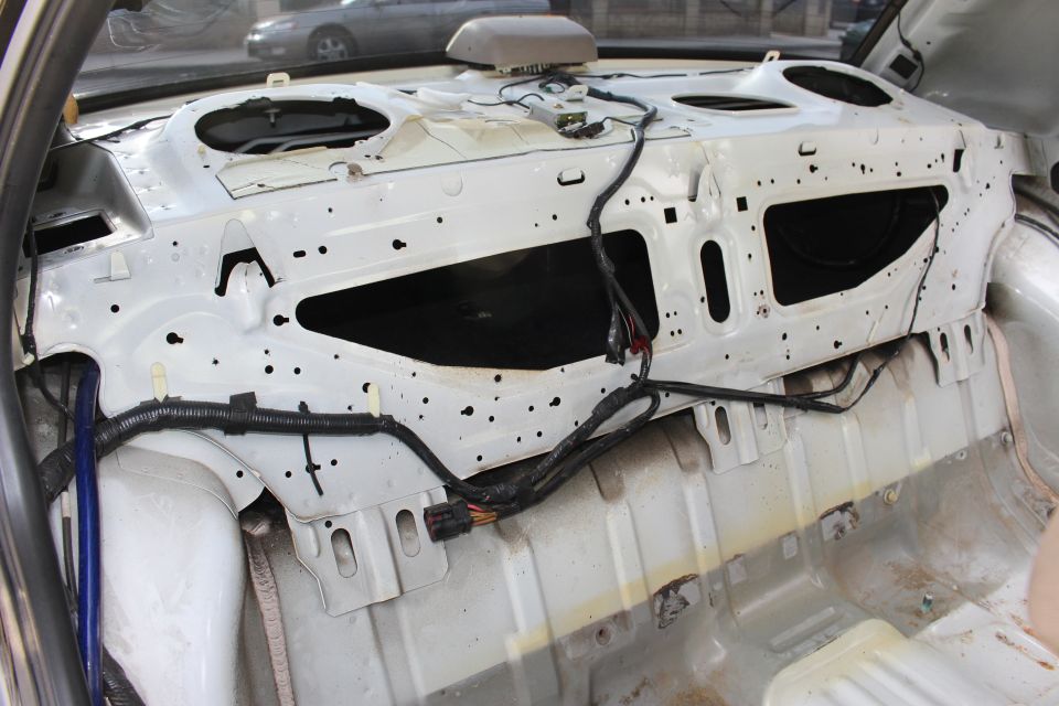 Bare rear bulkhead and package tray of a stripped sedan body shell