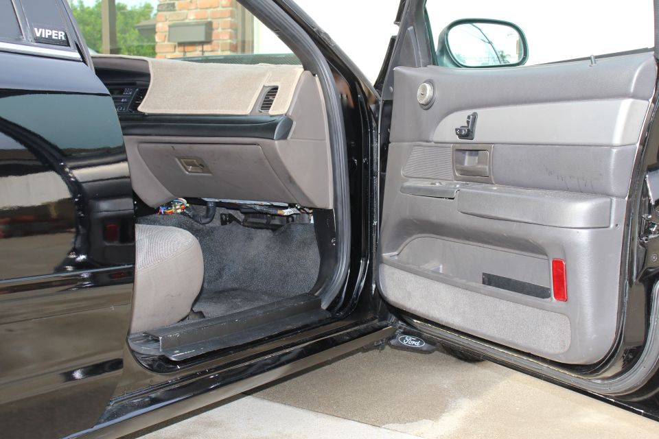 Open black car front door and gray door panel with Ford logo on the sill plate
