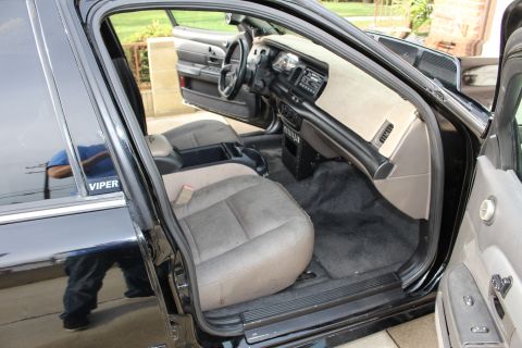 2003 Ford Crown Victoria - front interior of a black sedan seen through the open door, with a gray cloth seat, center console and gray dashboard.