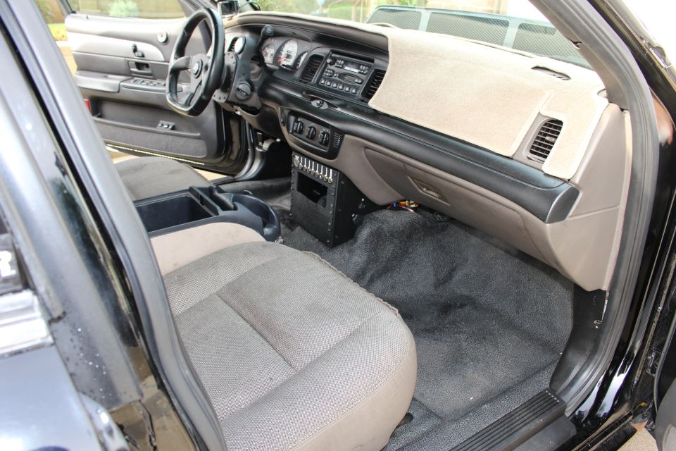 Interior dashboard and gray cloth front seats of a black sedan from passenger side