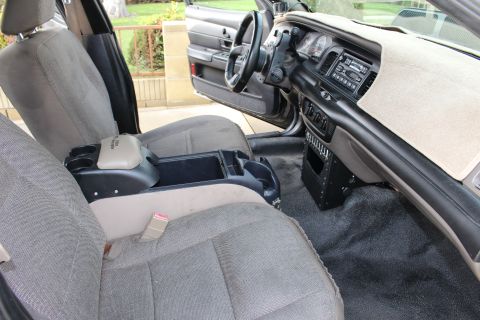 2003 Ford Crown Victoria - front cabin of a sedan with gray cloth bucket seats, a center console and gray dashboard, seen from the passenger side.