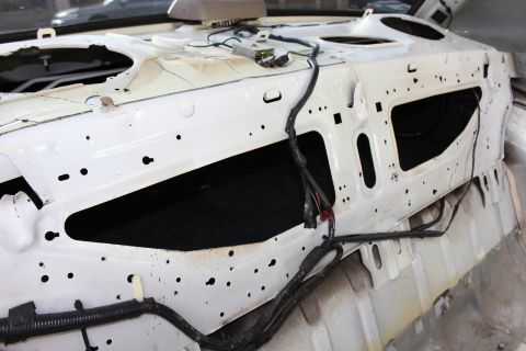 2003 Ford Crown Victoria - bare white-painted rear bulkhead of a sedan beneath the rear glass, with a wiring harness routed across the panel.
