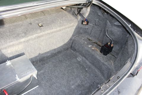 2003 Ford Crown Victoria - carpeted interior of a car trunk showing a metal battery box on one side and a small black canister mounted to the floor.