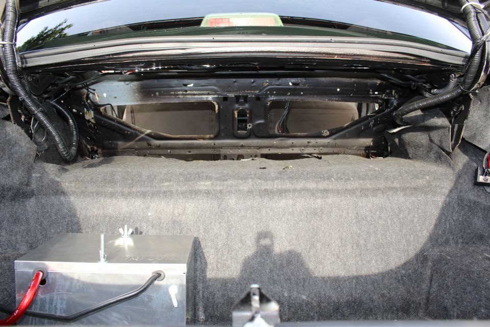 Rear trunk bulkhead of a car with carpet, a battery box and cabling