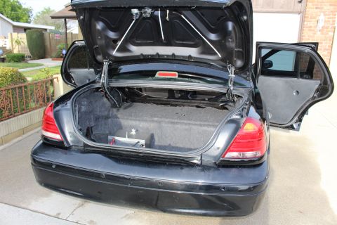 2003 Ford Crown Victoria - Photo of a black sedan with its trunk and rear door open in a residential driveway.