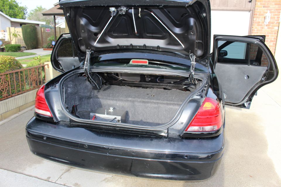 Open trunk and rear door of a black sedan parked in a driveway