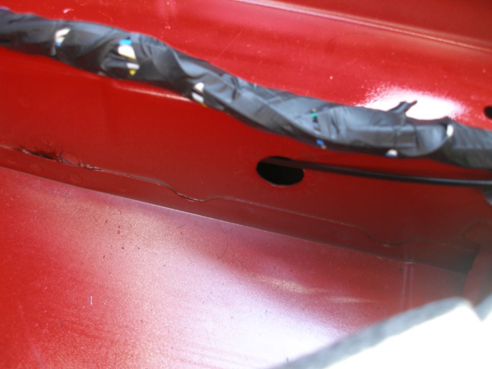 Close-up of red vehicle interior with black wire loom and opening.