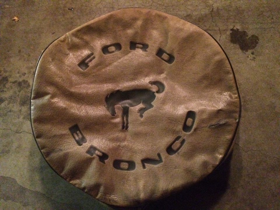 Brown leather Ford Bronco tire cover with embossed logo and text.