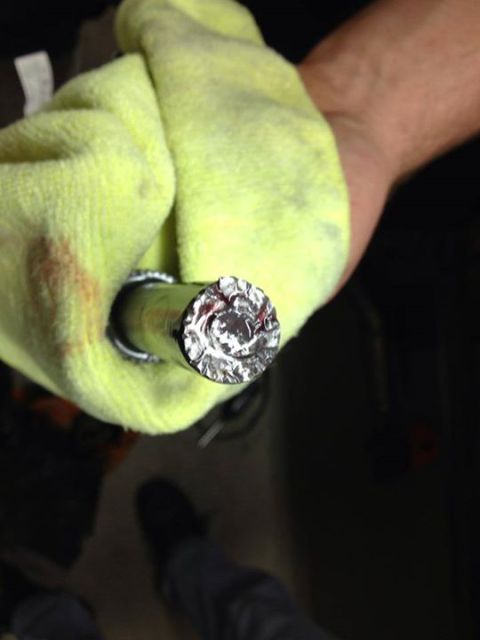 1992 Ford Crown Victoria - A hand holds a yellow microfiber cloth around a metal rod, revealing the end of the rod is covered in crumpled aluminum foil.