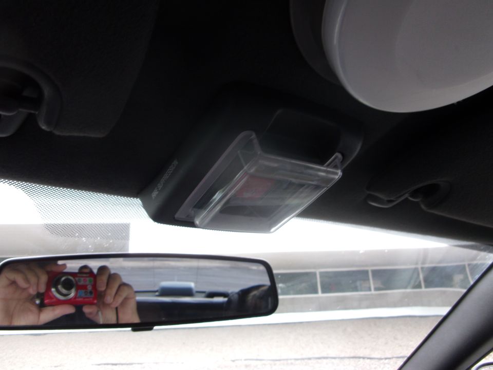 Overhead fire suppression switch cover with clear flip-up lid above rearview mirror in a car interior