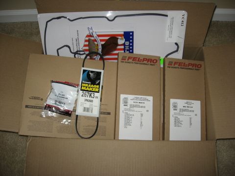 1994 Ford Bronco - An open cardboard box containing various automotive parts, including Fel-Pro gasket boxes, a drive belt, and a small bag with a PCV valve.…