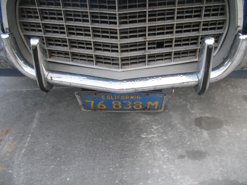Close-up of a vintage car's chrome bumper and grille with a California license plate.