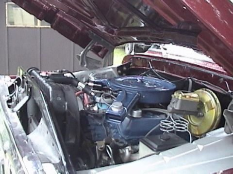 1979 Ford F-150 - The open hood of a maroon 1979 Ford F-150 reveals the engine bay, featuring a blue air cleaner and a gold brake booster assembly.