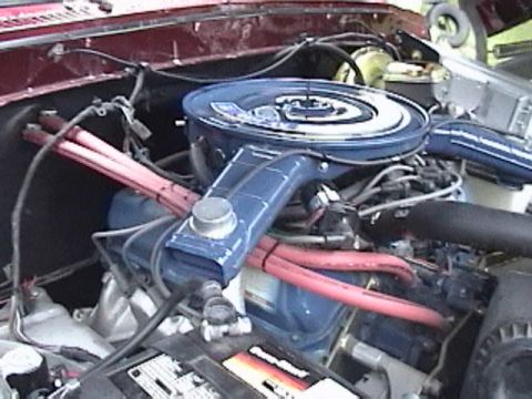1979 Ford F-150 - A close-up view of the engine bay of a classic Ford F-150, featuring a blue air cleaner assembly and red spark plug wires.