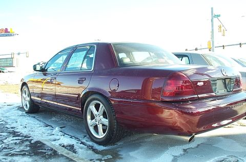 2001 Ford Crown Victoria - A maroon 2001 Ford Crown Victoria is parked on a lot with snow on the ground, seen from the rear quarter panel.