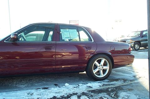 2001 Ford Crown Victoria - A maroon 2001 Ford Crown Victoria is parked on a snowy lot next to another vehicle.