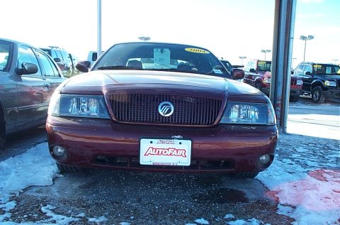 2001 Ford Crown Victoria - Maroon Mercury Grand Marquis parked outside a dealership with other vehicles visible.