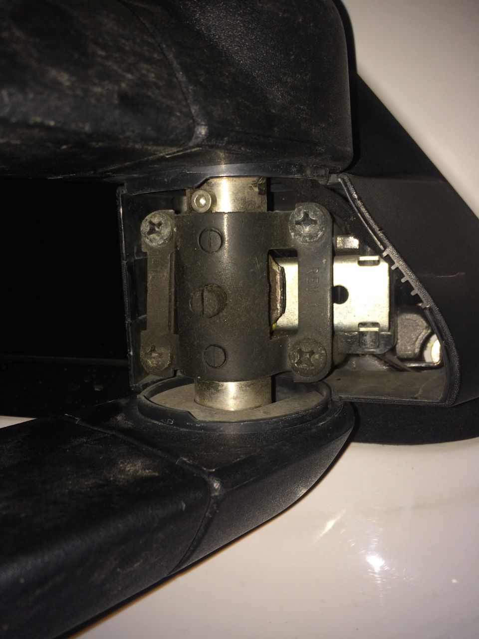 Close-up of a black seatbelt buckle mechanism with visible screws and metal latch.