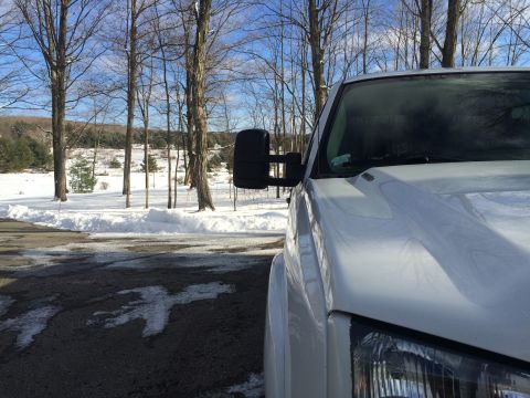 2006 Chevrolet Silverado 2500 - A white pickup truck is parked on a wet asphalt surface with snow piled up on the side. The truck is viewed from the front right quarter, w…