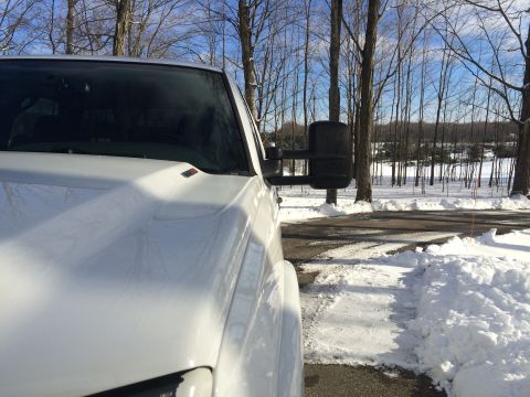 2006 Chevrolet Silverado 2500 - A white Chevrolet pickup truck is parked on an asphalt surface with snow on the ground and trees in the background. The photo is taken from…