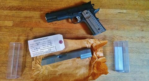 1996 Ford Bronco - A disassembled firearm slide rests on brown paper next to an inspection report tag and a complete firearm on a wooden surface. The inspecti…