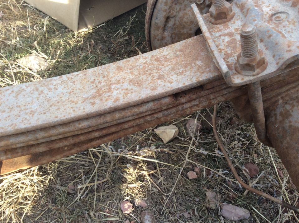 Rusted leaf spring assembly on a vehicle axle.