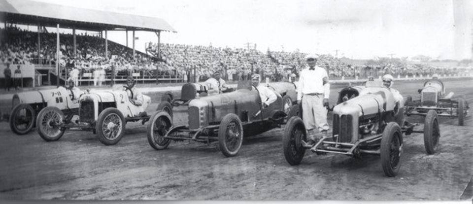 Race cars lined up with spectators in the background