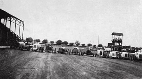 1909 Ford Model T - A line of vintage cars are parked on a track, possibly before a race or event.
