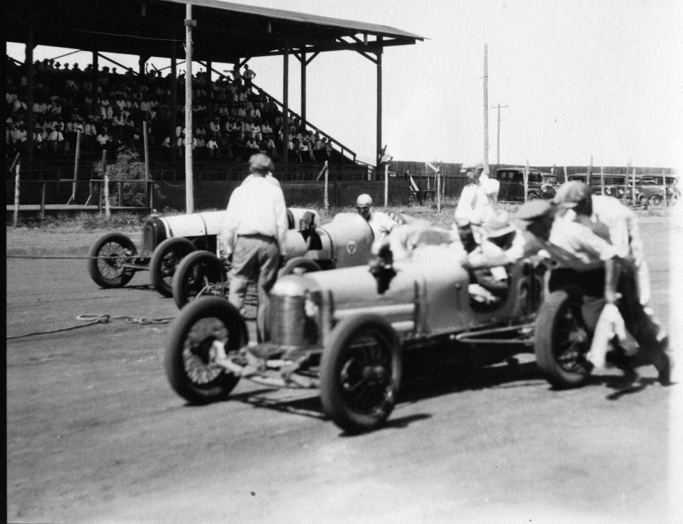 1909 Ford Model T race cars lined up at a track with spectators in bleachers