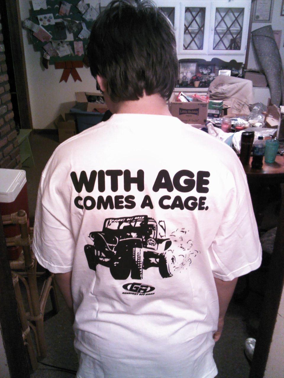 White t-shirt with graphic of a Jeep and text 'WITH AGE COMES A CAGE.'
