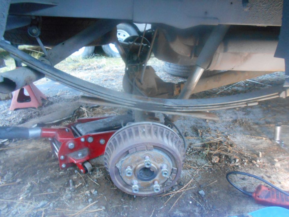 Rear axle assembly with leaf springs, brake drum, and hydraulic jack
