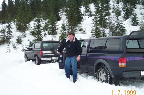 1995 Ford Bronco - A dark gray Ford Bronco is partially buried in snow, with a man standing nearby.