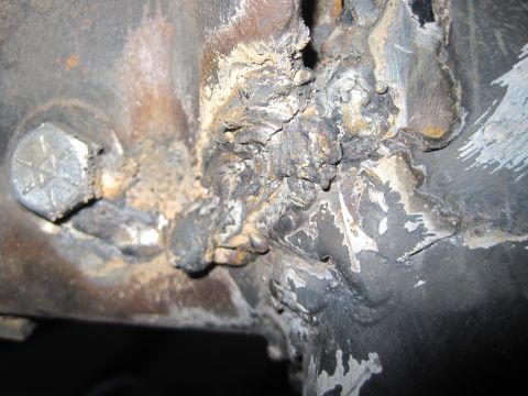 1989 Ford Bronco - A heavily corroded and welded metal joint is visible, secured by a hex bolt.
