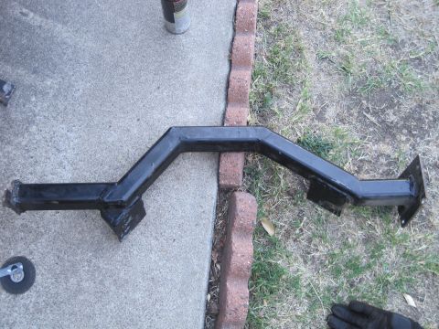 1989 Ford Bronco - A black metal trailer hitch receiver is shown lying on concrete and grass.