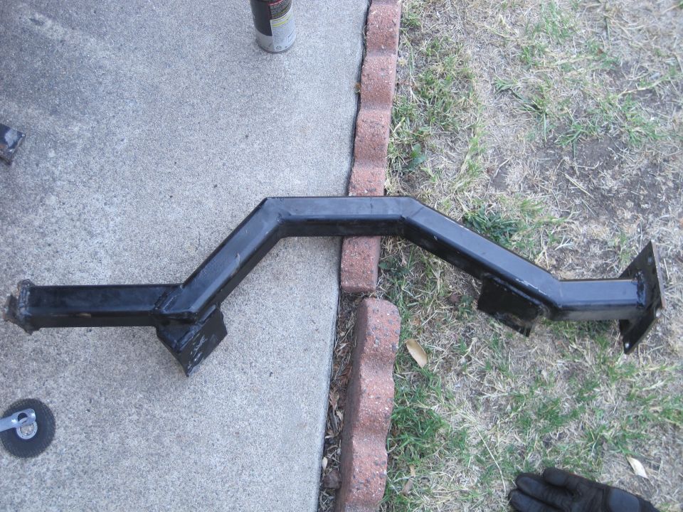 Black metal trailer hitch receiver on concrete and grass