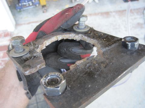 1989 Ford Bronco - A heavily damaged metal bracket, held by a gloved hand, reveals significant wear and tear.