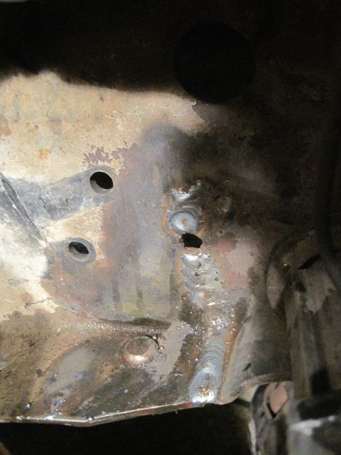 1989 Ford Bronco - Close-up view of a heavily rusted metal frame section showing numerous welds and drilled holes.