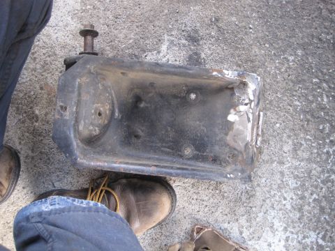 1989 Ford Bronco - A close-up view of a worn metal bracket with a bolt protruding from its top surface.