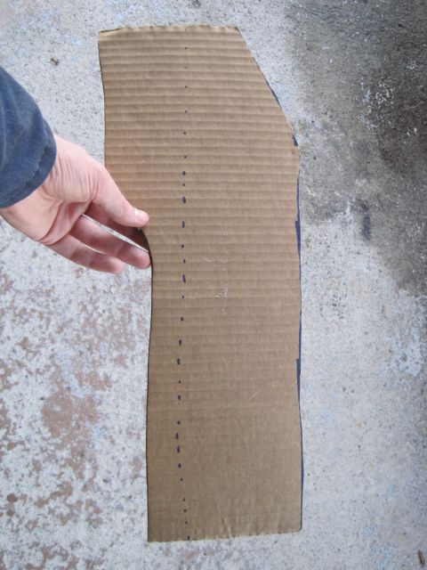 1989 Ford Bronco - A hand holds a cardboard template marked with a dotted line, likely for a part.