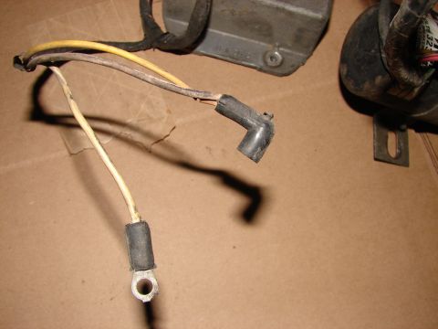 1973 Ford Ranchero - A collection of automotive electrical parts, including wiring, a spark plug boot, and other components, are laid out on a cardboard surface.