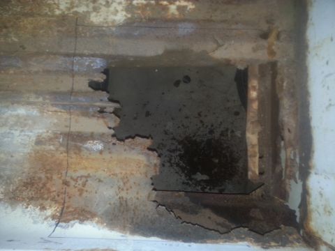 1973 Ford F-100 - Close-up of heavily rusted metal with a significant hole, revealing a dark interior space.