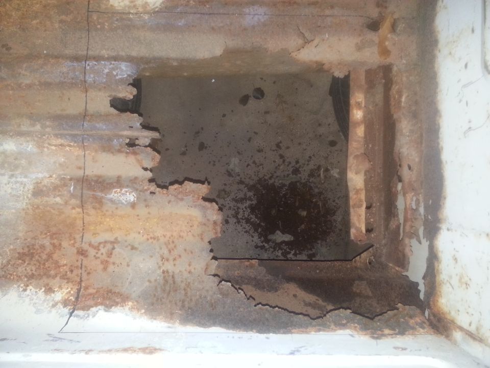 Heavily rusted metal frame with a large hole, showing internal structure